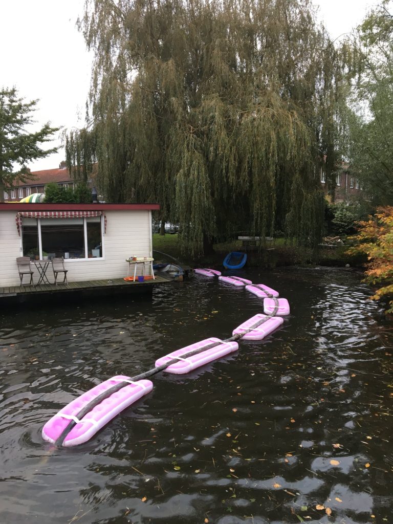 Roze luchtbedden om de betonslang over het water te krijgen