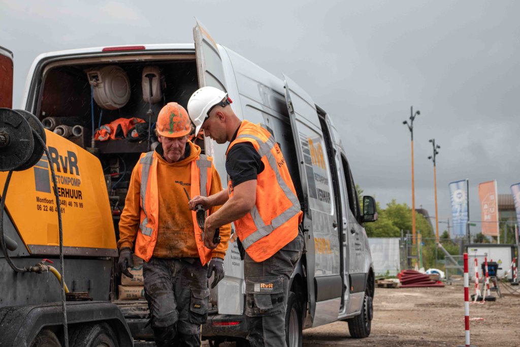 Twee medewerkers gebruiken een klem voor betonslang om beton efficiënt te verwerken op de bouwplaats van DuraVermeer